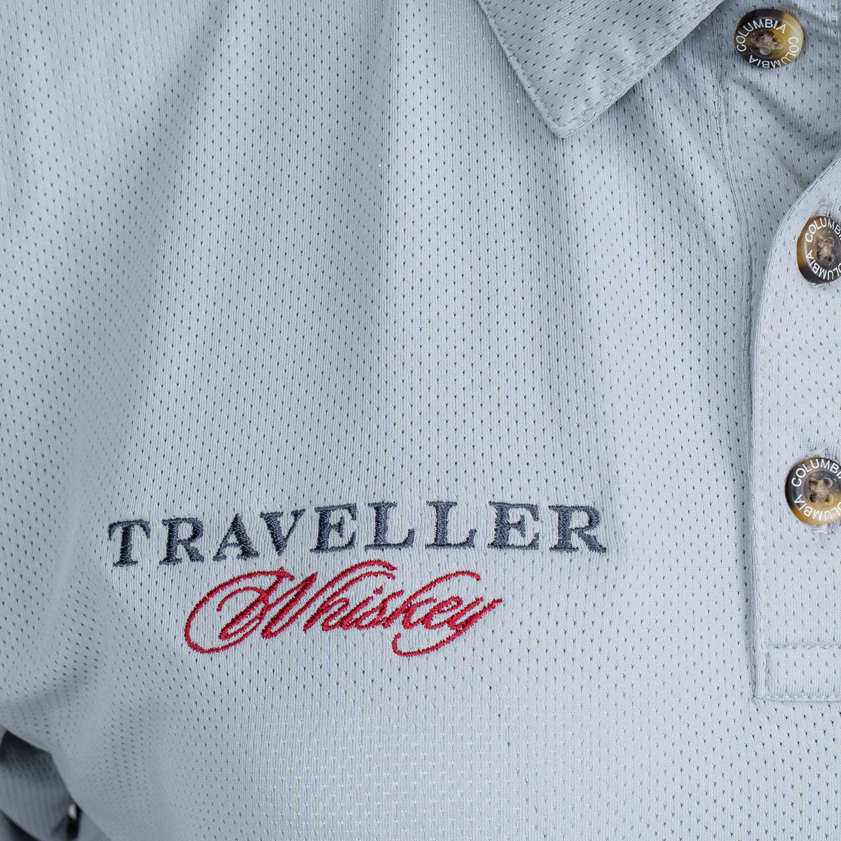 Traveller Columbia Grey Polo close-up of embroidered Traveller Whiskey logo on left chest